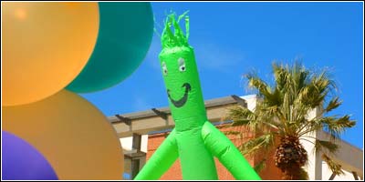 multi-colored ballons in foreground, large green smiling balloon man in background...